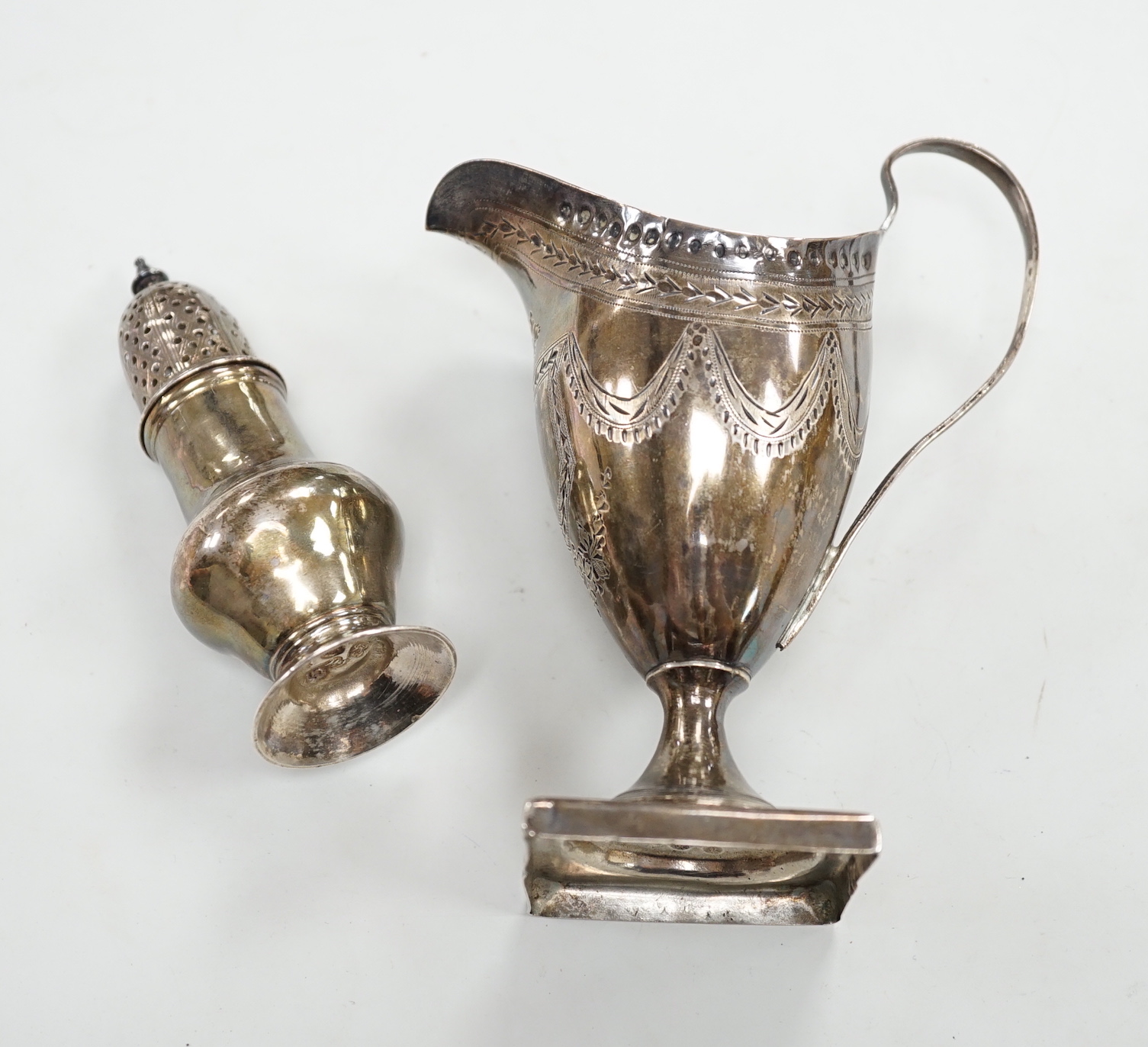 A George III silver helmet shaped cream jug, on square base, London, 1791 (overstruck maker's mark), 14.3 cm(a.f.) and a George II silver pepperette, London, 1755, (a.f.), 5.4oz.